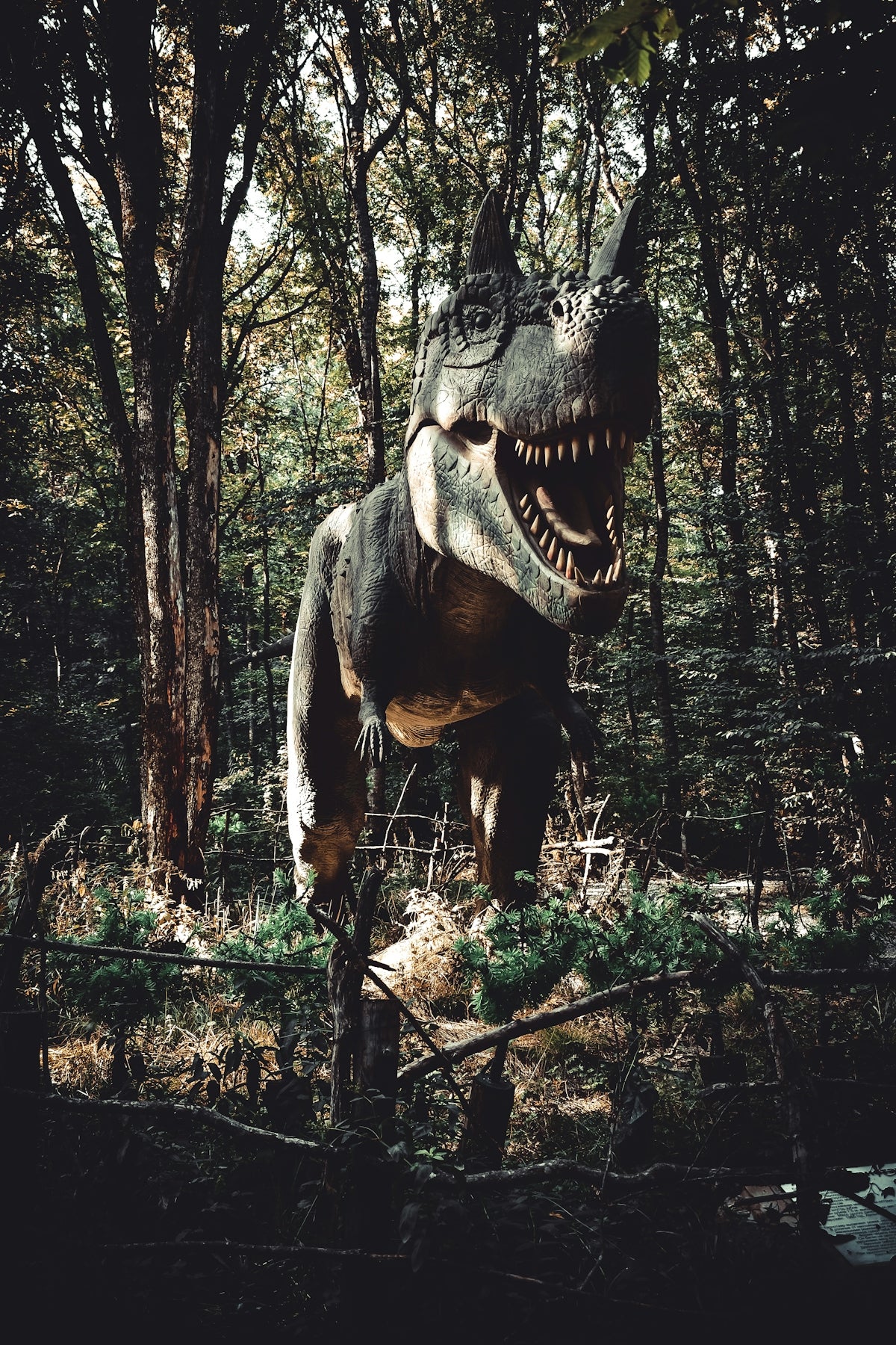 brown dinosaur beside tree