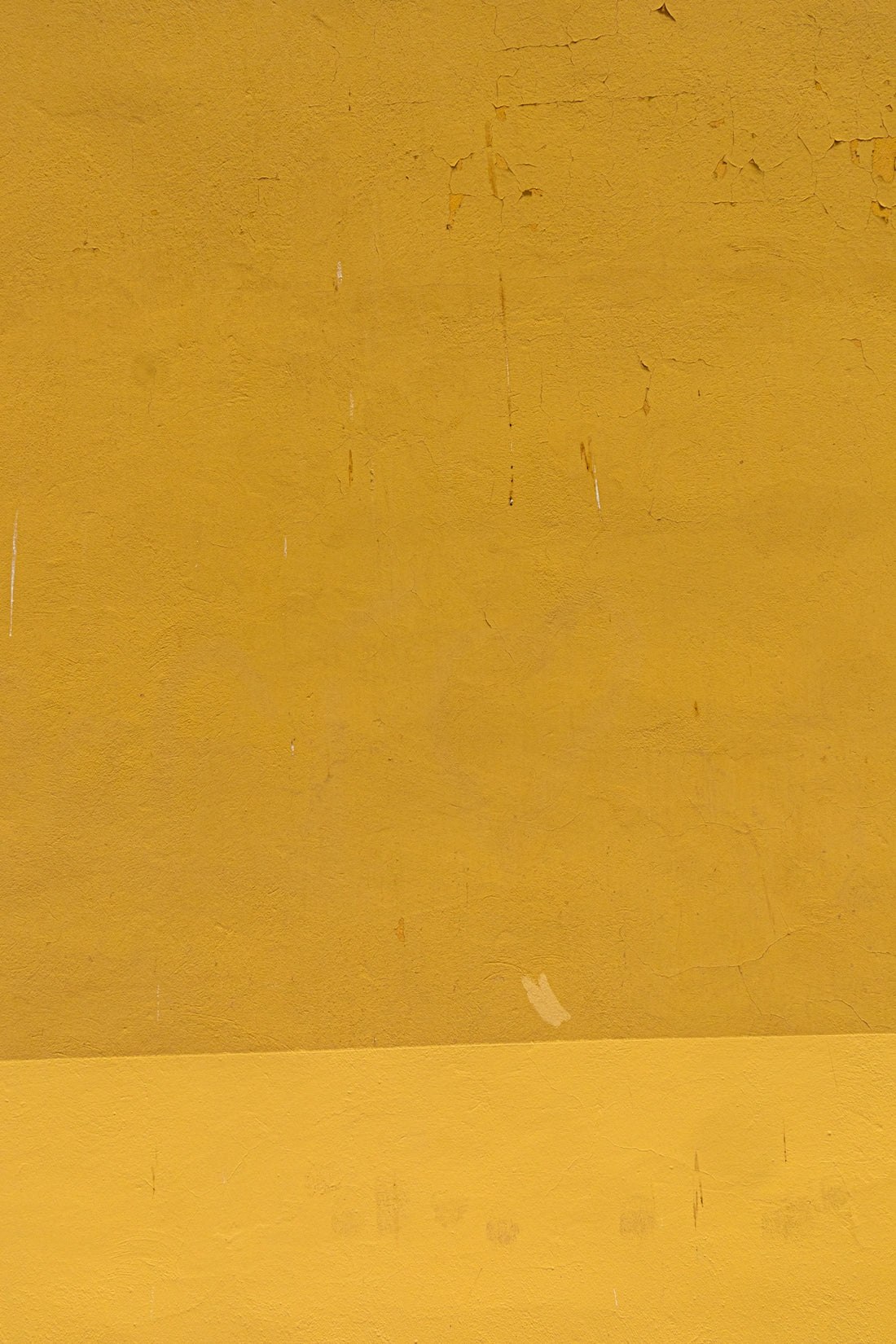 a man riding a skateboard down a street next to a yellow wall