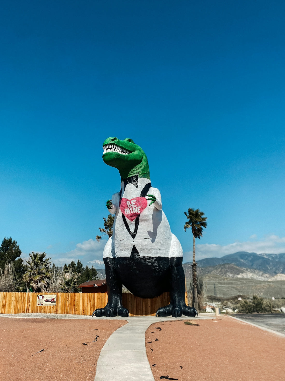 a large inflatable dinosaur sitting on top of a sidewalk