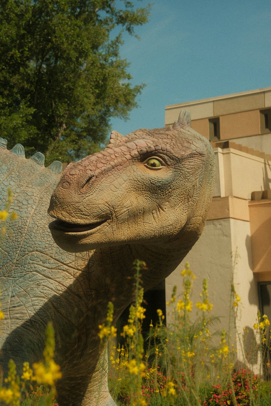 A dinosaur statue stands next to a building