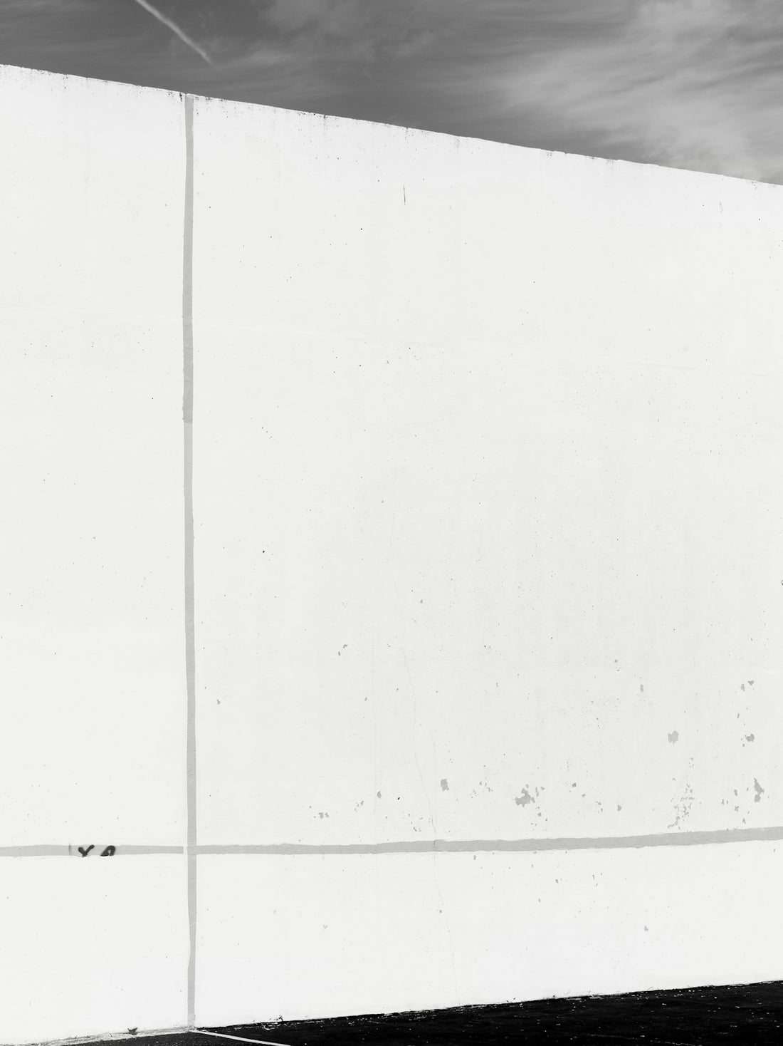 A stark white wall with subtle lines against sky