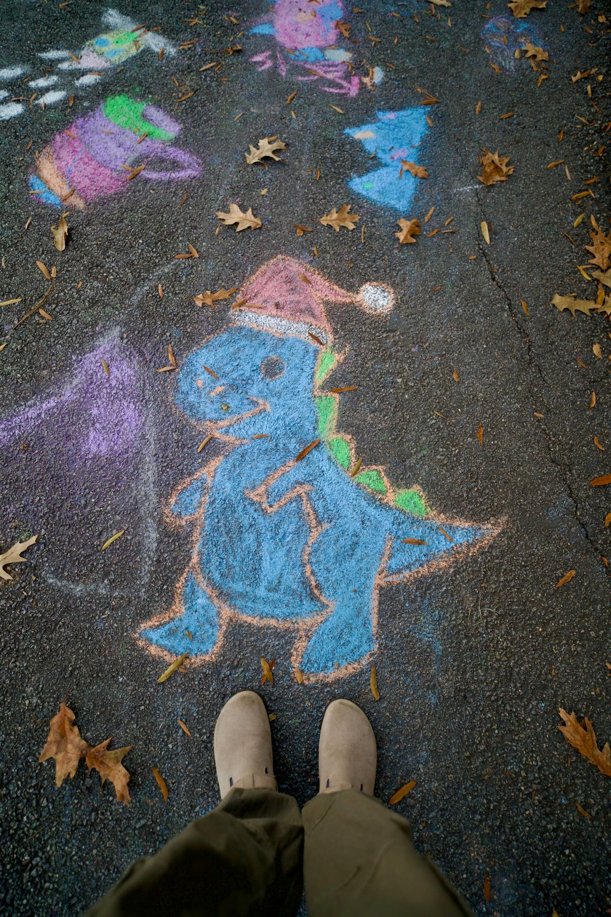Chalk drawings of dinosaurs and other figures on pavement
