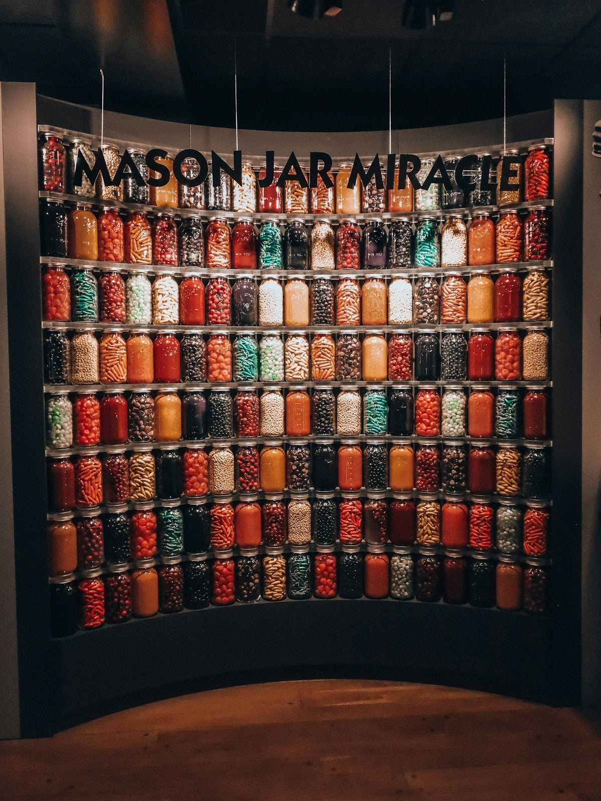 Many colorful mason jars displayed on a wall